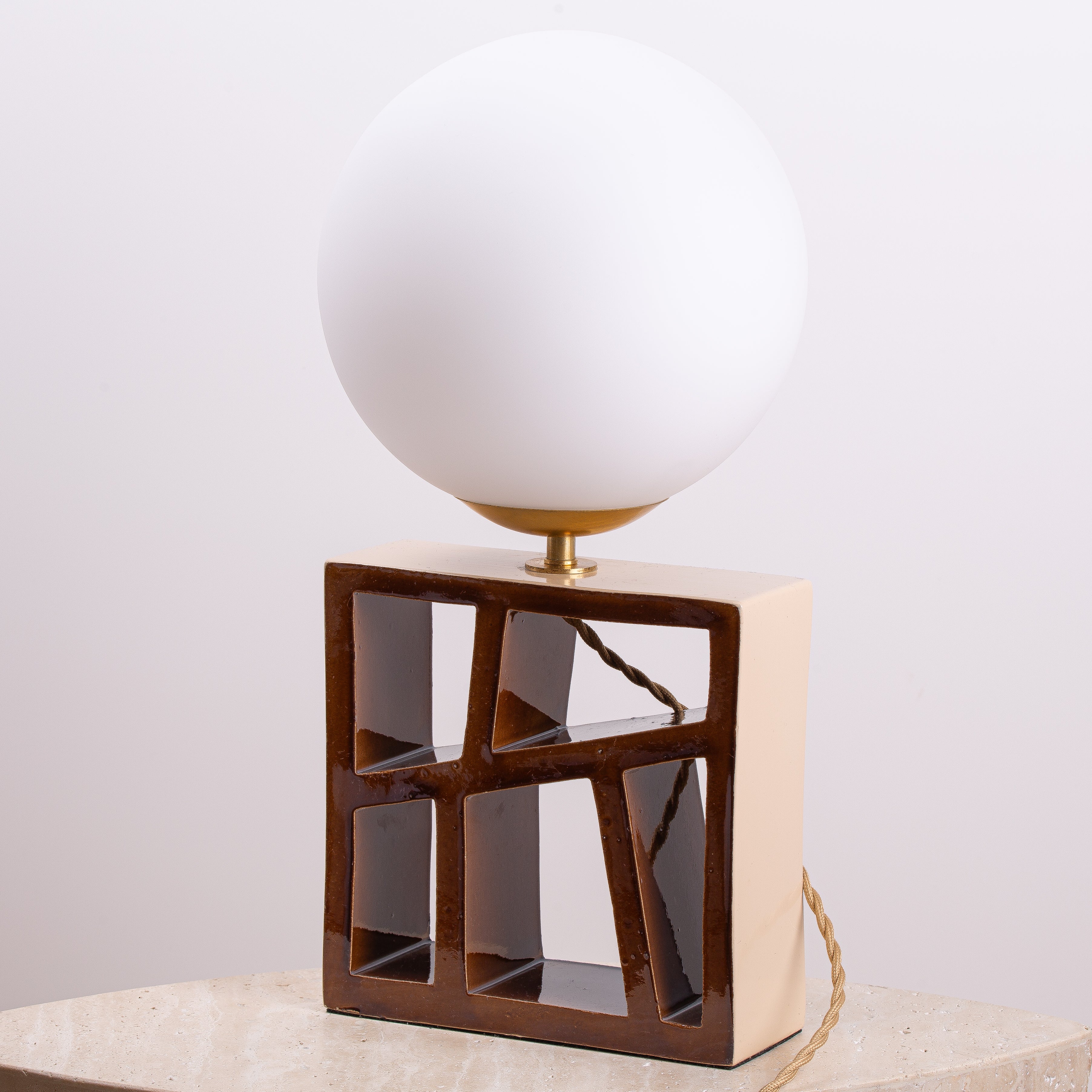 Lampe RÉALISE à globe opalin sur socle géométrique en céramique émaillée brune, détail laiton.